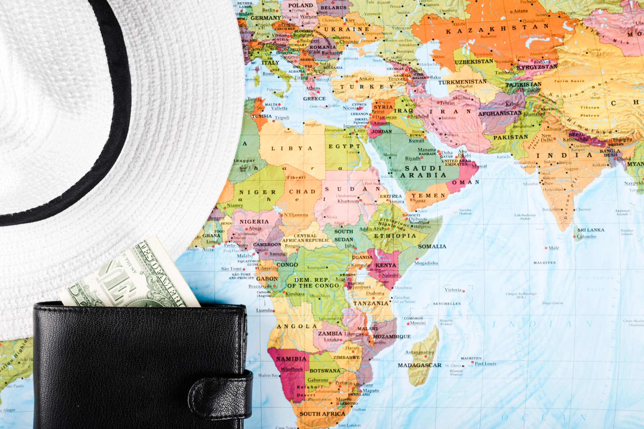 Un chapeau et un portefeuille posés sur une carte du monde centrée sur l'Afrique