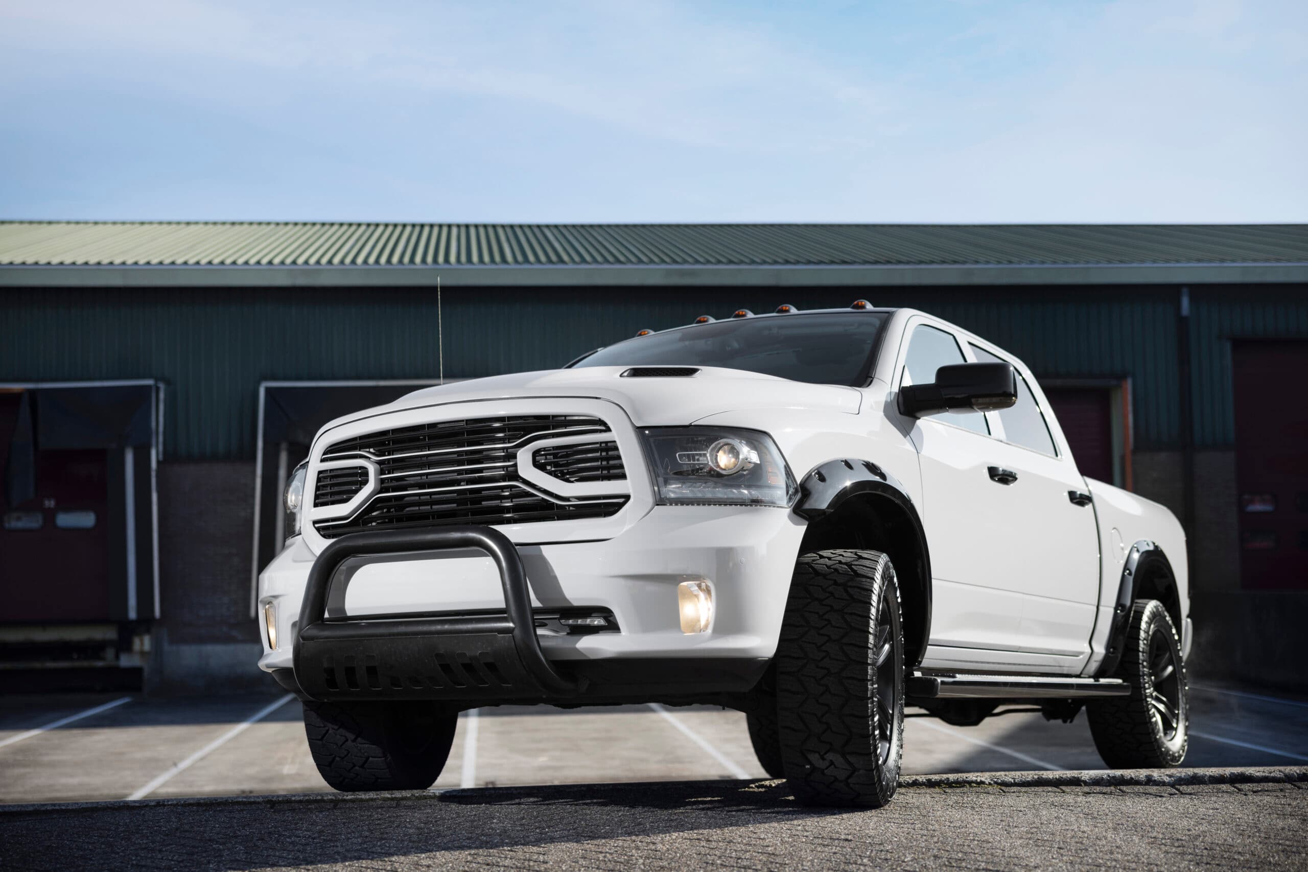 Pick-up blanc photographié en contre-plongée devant un entrepôt